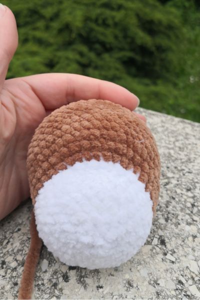 Pizsamás amigurumi kutyus feje Himalaya fonalból horgolva, tömés előtt kézben tartva.